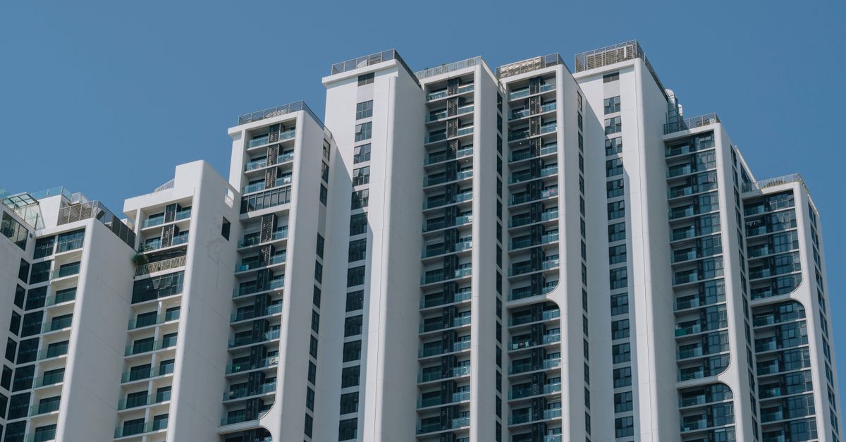 Contemporary high-rise apartment building with unique design and glass facades against a clear blue sky.